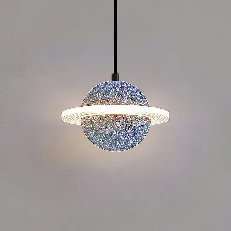 A grey blue speckled Clérachic pendant with a lit ring hangs on a black cord against a plain grey wall.
