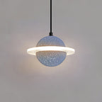 A grey blue speckled Clérachic pendant with a lit ring hangs on a black cord against a plain grey wall.