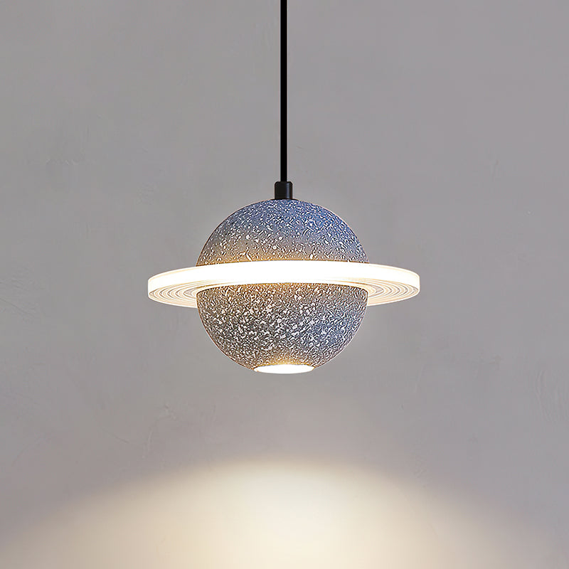 Lit grey blue Clérachic pendant with a bright ring and a pool of warm light below it on a grey wall.