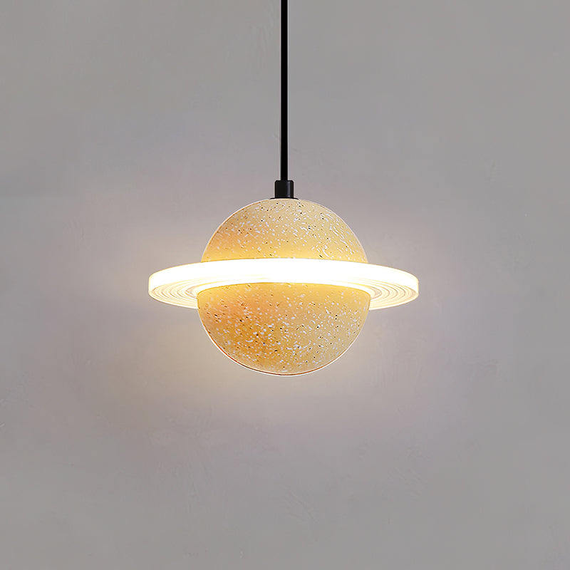 Sand yellow Clérachic pendant with a bright glowing ring and a warm halo behind it on a grey wall.