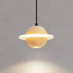 A sand yellow Clérachic pendant with a lit ring casts a warm pool of light downwards on a grey wall.