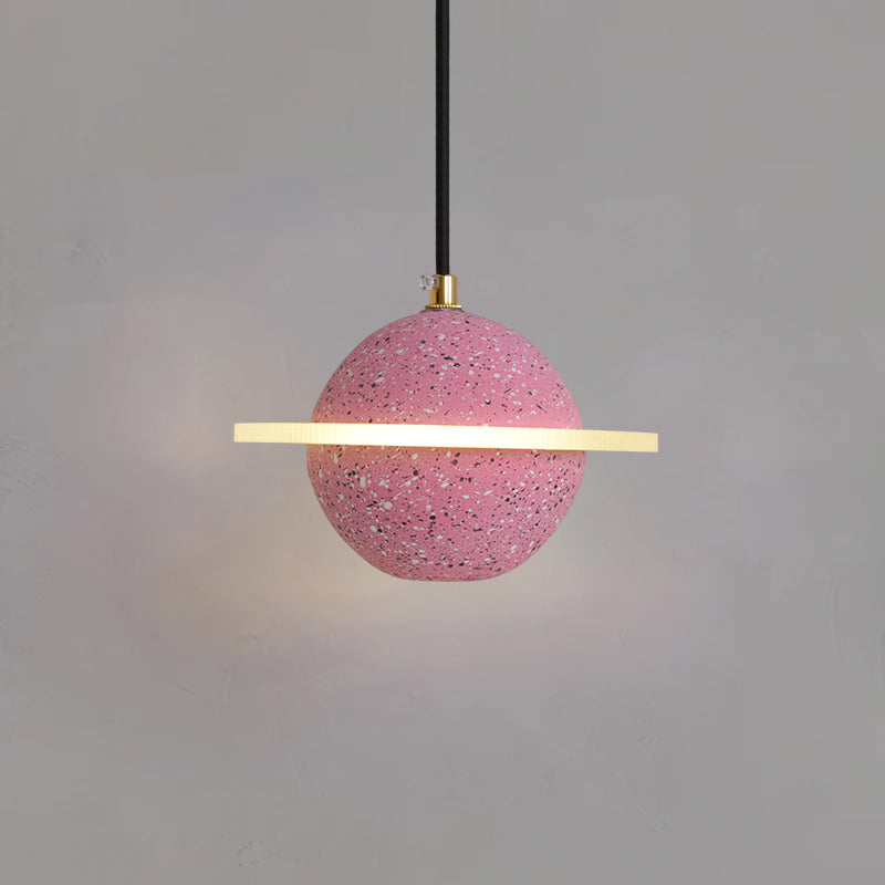 Sand pink Clérachic pendant with a flat glowing ring and brass cord top, hanging against a grey wall.