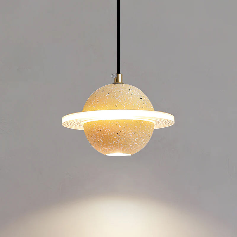 A sand yellow Clérachic pendant with a bright ring and downlight, with warm light pooling on the grey wall below.
