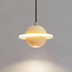 A sand yellow Clérachic pendant with a bright ring and downlight, with warm light pooling on the grey wall below.