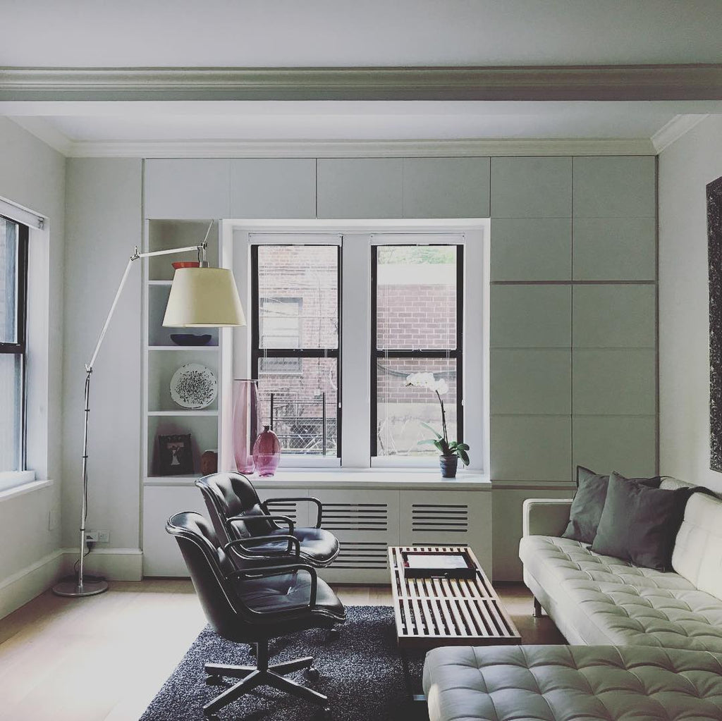 Clérachic arc floor lamp in a pale living room with a window, black leather chairs and a quilted grey sofa.