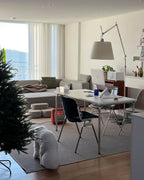 Clérachic floor lamp with a grey shade in a bright open-plan room with a desk, a dark chair and a window with sheer curtains.
