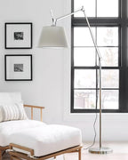 Clérachic floor lamp with a pale shade beside a black-framed window, over a white daybed and two framed prints.