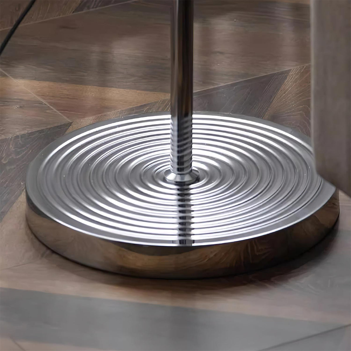Close view of the ringed, polished metal base where the pole meets the floor on this Clérachic floor lamp.