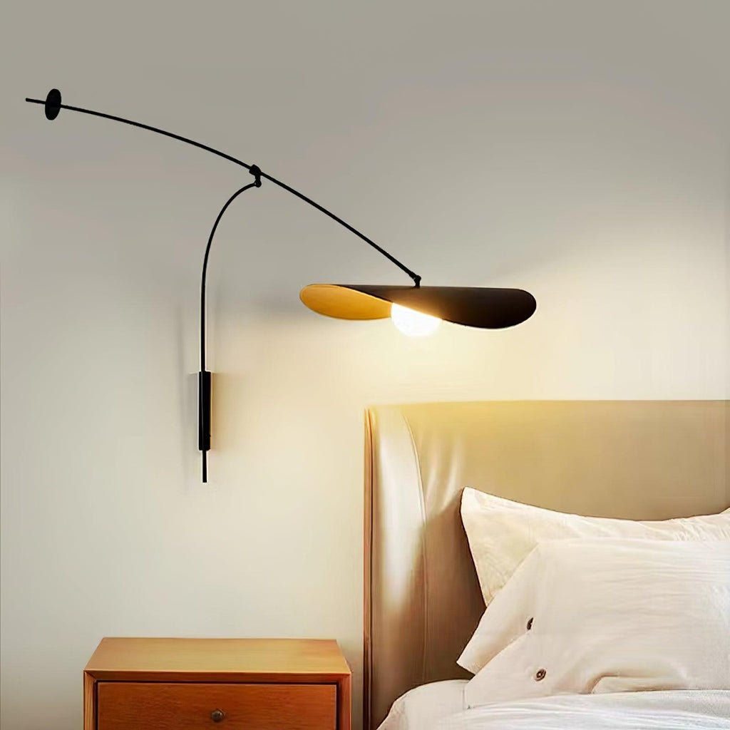 This Clérachic wall light lit above a wooden nightstand, with a tan leather headboard and white bedding behind it.