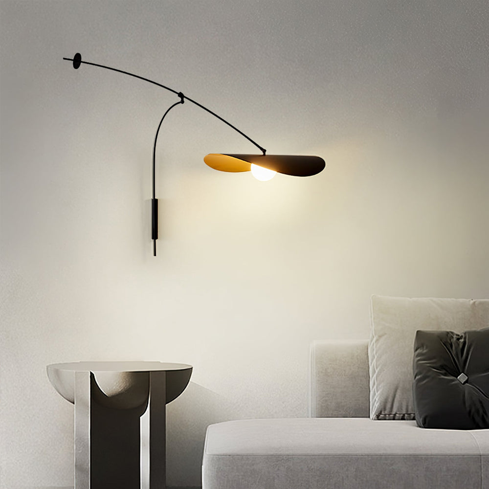 A Clérachic wall light on a plain wall with a stone side table and a grey sofa below, the shade glowing gently.