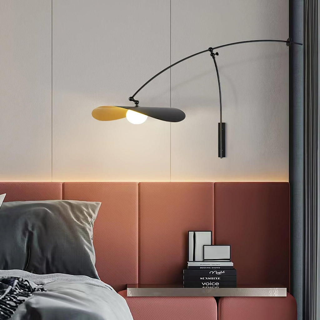 Over a dusty-pink padded headboard, this Clérachic wall light angles its gold-lined shade down beside a dark curtain.