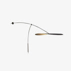 Side view of a Clérachic wall light on white, the shade tipped almost edge-on to show its thin black and gold profile.