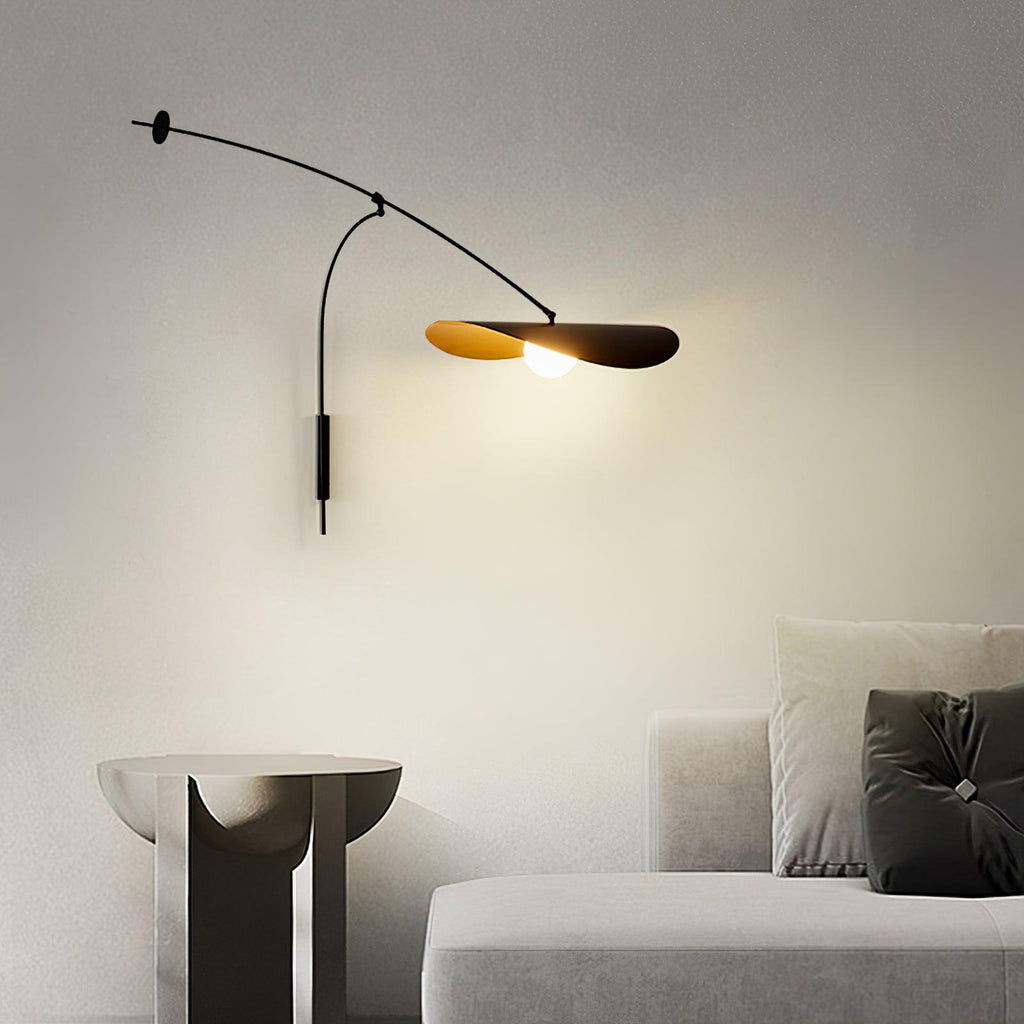 A Clérachic wall light glows warm over a stone side table and a pale sofa with dark cushions in a grey room.
