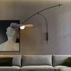 Over a grey sofa and a framed classical bust, this Clérachic wall light hangs against a dark, ribbed wall.