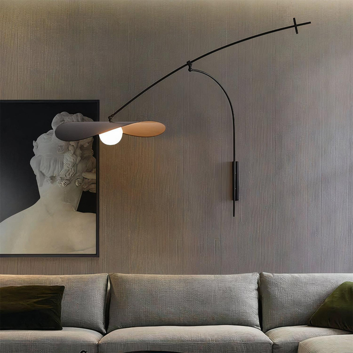 Over a grey sofa and a framed classical bust, this Clérachic wall light hangs against a dark, ribbed wall.