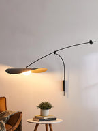 This Clérachic wall light lights a plant on a round side table, with a leather armchair at the left edge.