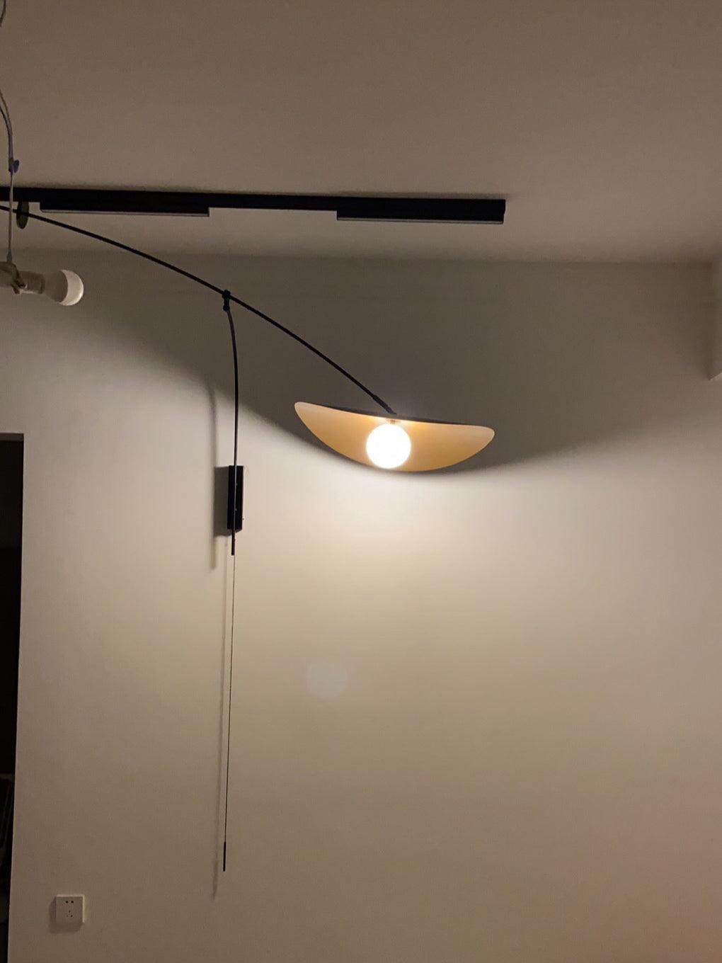 Unlit by day, this Clérachic wall light shows a pale shade under a ceiling track, with its cord switch hanging below.