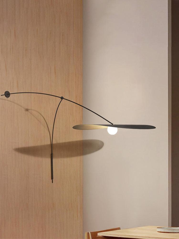 The black arm and flat shade of this Clérachic wall light cast a soft shadow on a pale wall beside oak panelling.