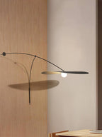 The black arm and flat shade of this Clérachic wall light cast a soft shadow on a pale wall beside oak panelling.