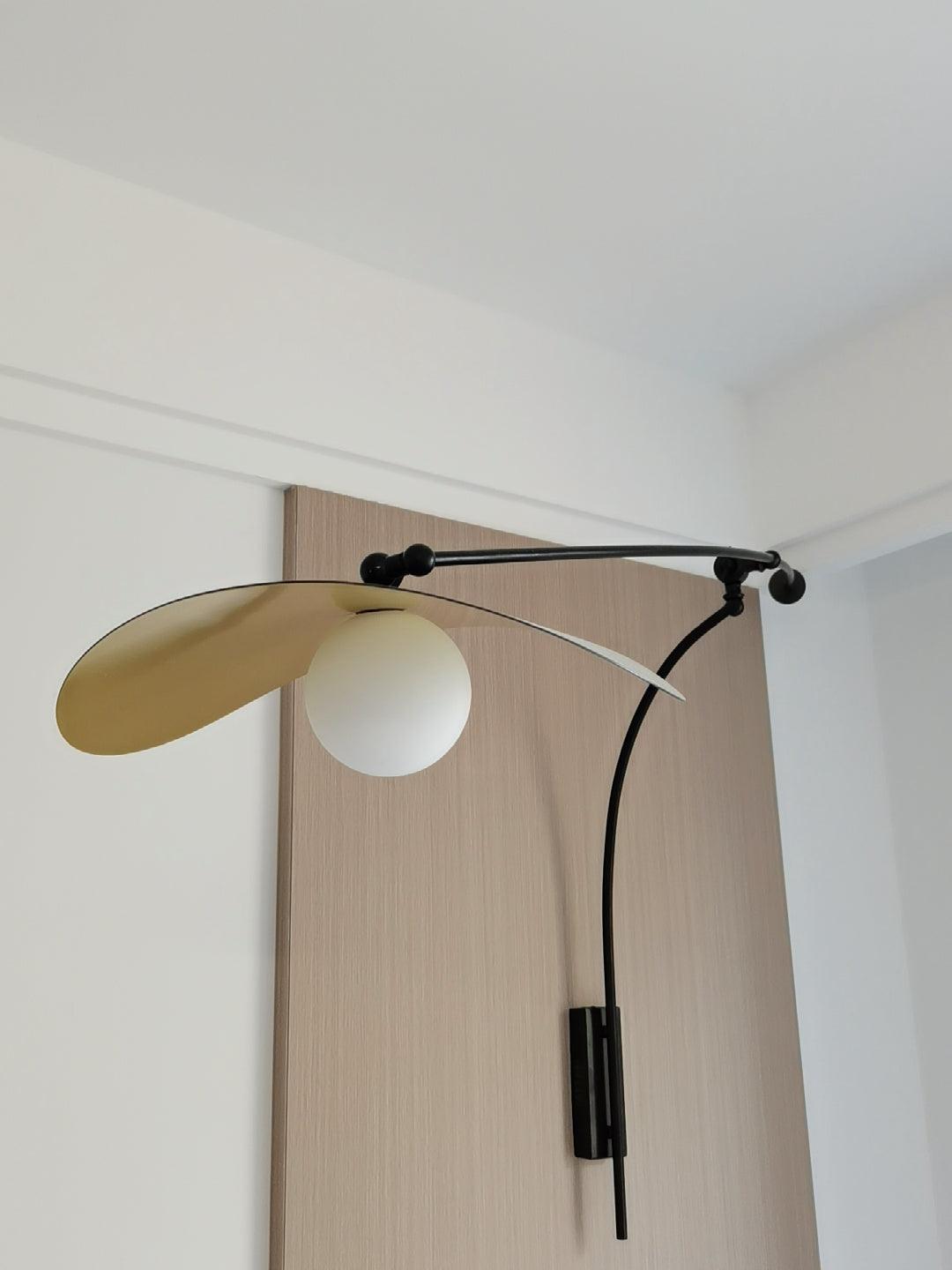 Looking up at this Clérachic wall light on an oak-veneer panel, the gold-lined shade tipped upward over a white globe.