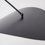Close view of the black upper side of this Clérachic wall light's shade, with the pivot joint where the arm meets it.
