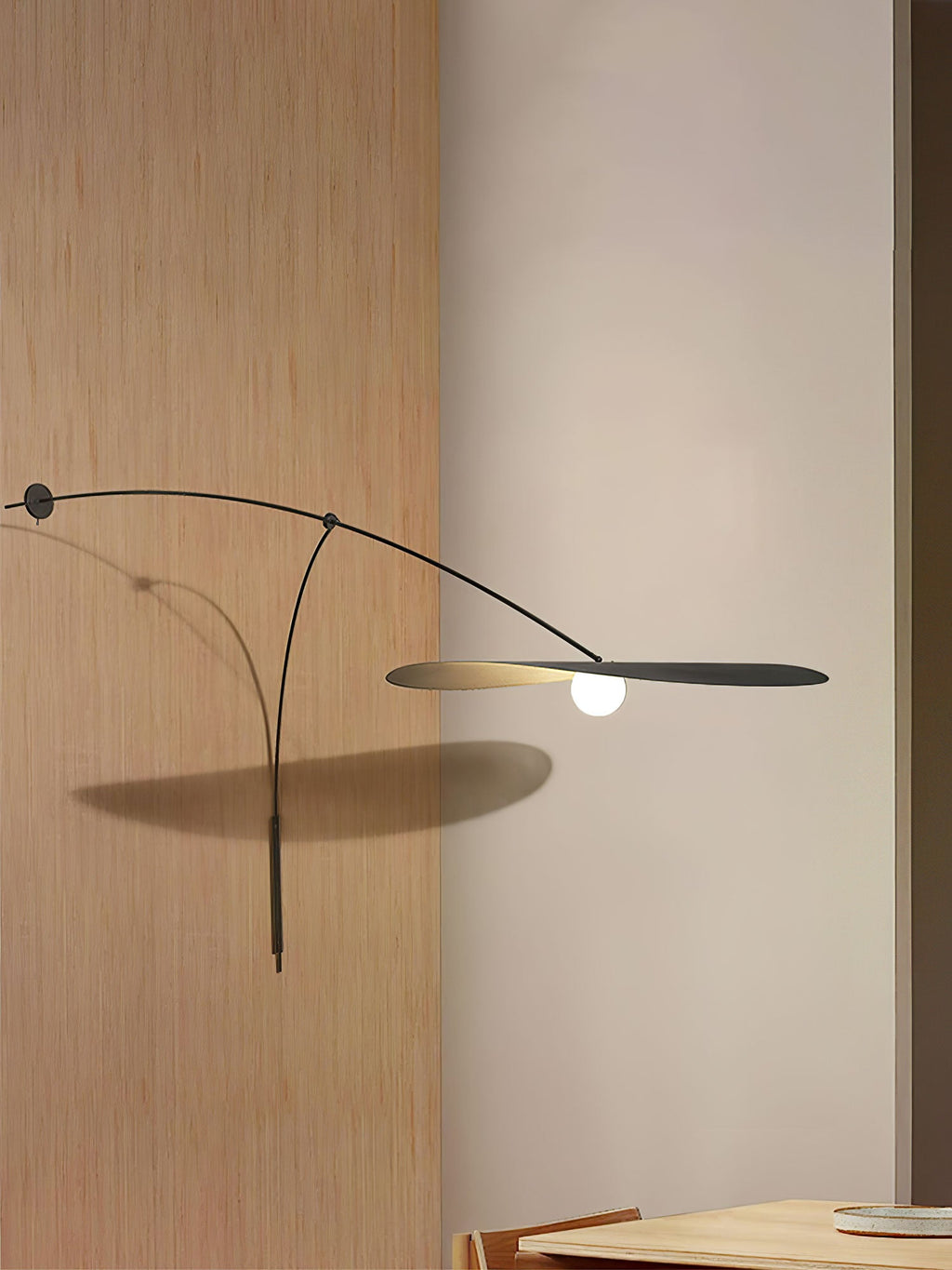 The black arm of this Clérachic wall light stretches across oak panelling, its shade casting a soft shadow.