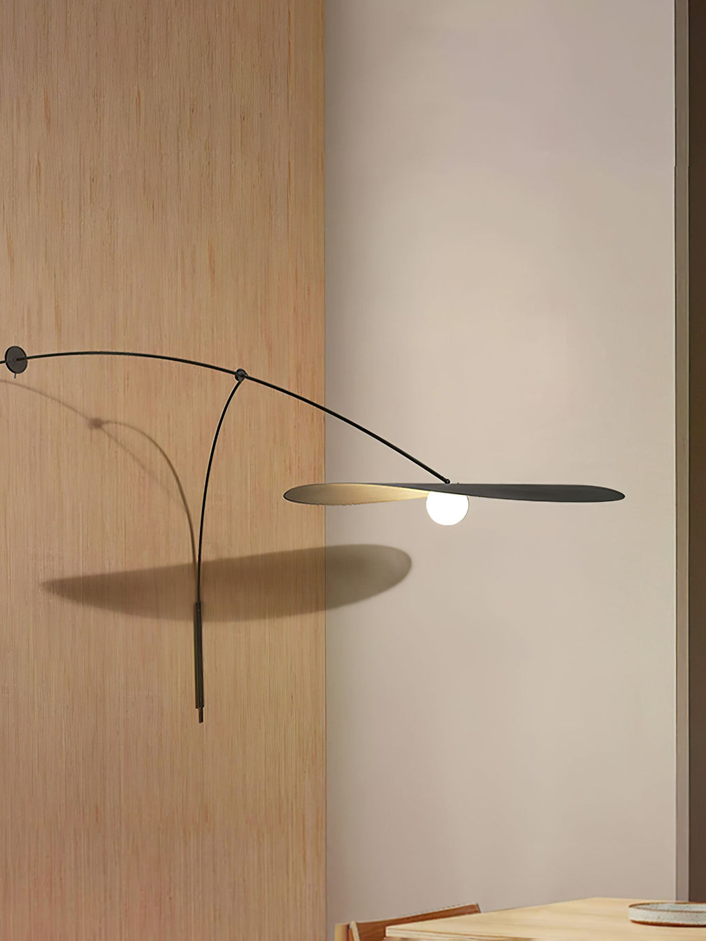 Tall crop of a Clérachic wall light on cream plaster beside an oak panel, the shade casting a shadow on the wall.