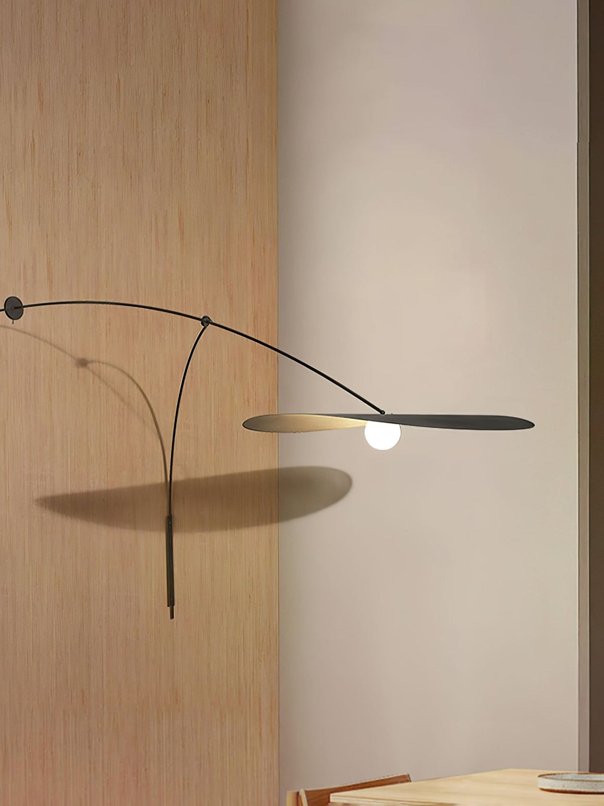 Tall crop of a Clérachic wall light on cream plaster beside an oak panel, the shade casting a shadow on the wall.