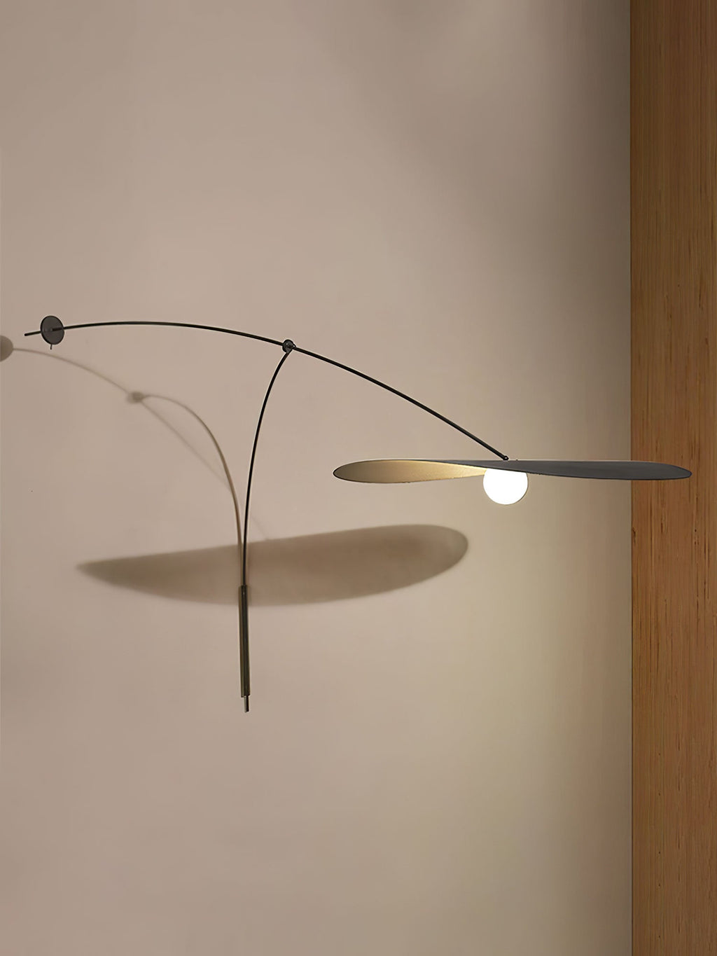 Close to a beige wall, this Clérachic wall light stretches its black shade flat and throws an angled shadow below.