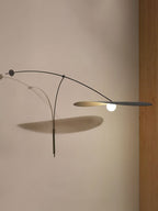 Close to a beige wall, this Clérachic wall light stretches its black shade flat and throws an angled shadow below.