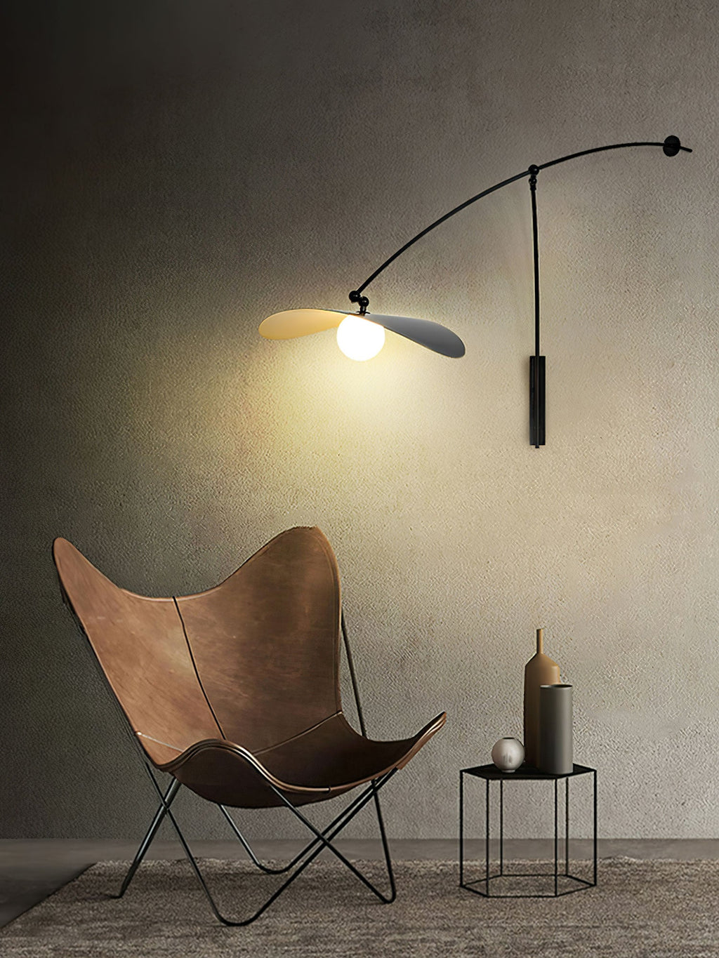 Warm bulb light from this Clérachic wall light on a dark textured wall, with a leather butterfly chair below.
