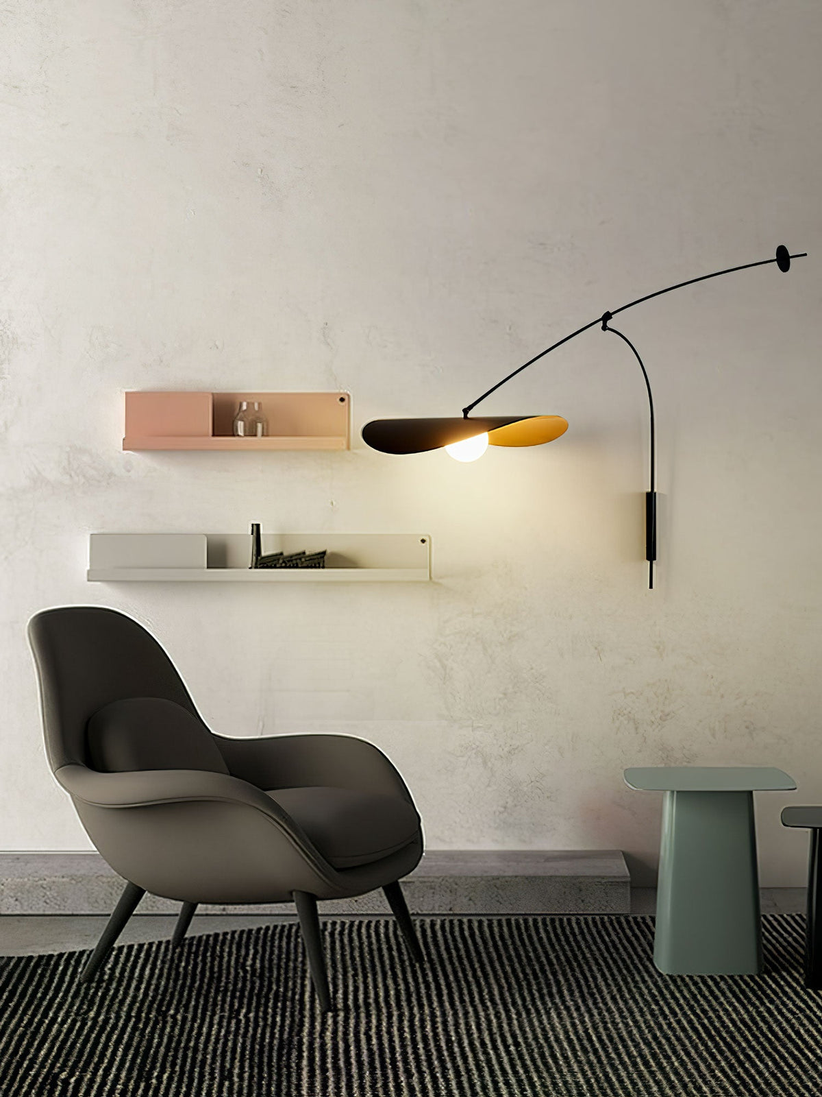 Beside a dark armchair and two pale wall shelves, this Clérachic wall light glows above a striped rug.