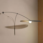 On a warm beige wall, this Clérachic wall light stretches its flat black shade out with a long shadow below it.