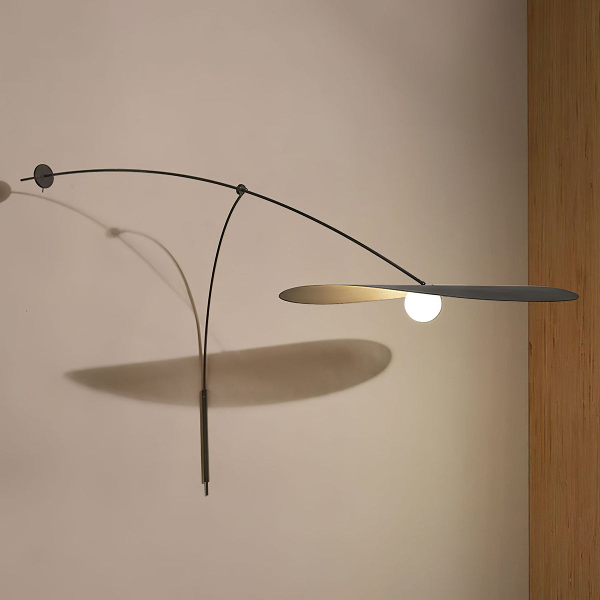 On a warm beige wall, this Clérachic wall light stretches its flat black shade out with a long shadow below it.