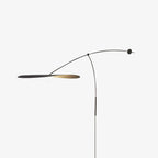 Studio view of a Clérachic wall light on light grey, with the shade turned edge-on and a thin black stem.