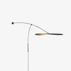 This Clérachic wall light on a pale backdrop, the shade turned edge-on, with a thin black stem and a round wall plate.