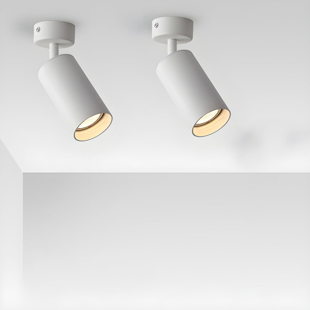 A pair of white Clérachic spotlights on short arms, tilted at different angles and casting a warm glow from a white ceiling.