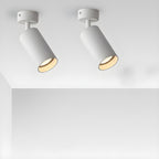A pair of white Clérachic spotlights on short arms, tilted at different angles and casting a warm glow from a white ceiling.