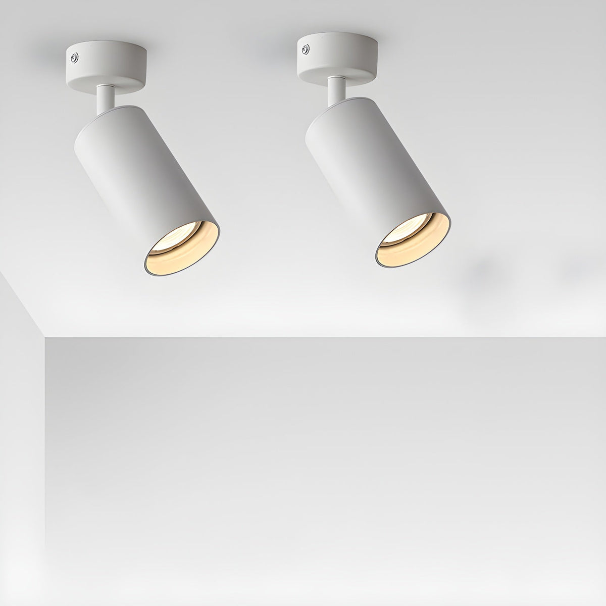 A pair of white Clérachic spotlights on short arms, tilted at different angles and casting a warm glow from a white ceiling.