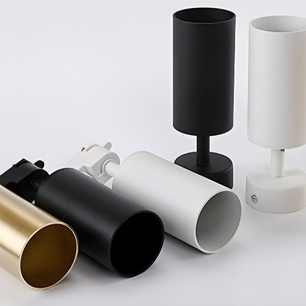 Black, white and gold cylinder shades of this Clérachic spotlight laid out together, with the open shades and canopies showing.