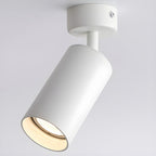 Large close-up of this Clérachic spotlight in white, the cylinder tipped on its stem and the warm bulb glowing inside the rim.