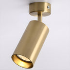 Close view of the brushed gold cylinder and canopy on this Clérachic spotlight, with a warm glow inside the shade.