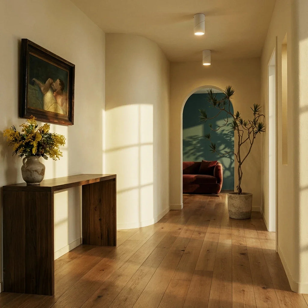 Two white adjustable downlights line a sunlit hallway ceiling above a wood console and archway, these Clérachic fixtures set flush.