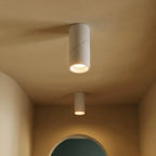 Two white adjustable downlights glow along a warm hallway ceiling near an archway, these Clérachic fixtures seen close and angled.