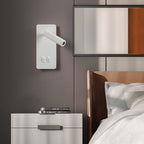 The white Clérachic reading light on a grey bedroom wall, spot turned in toward the bed.