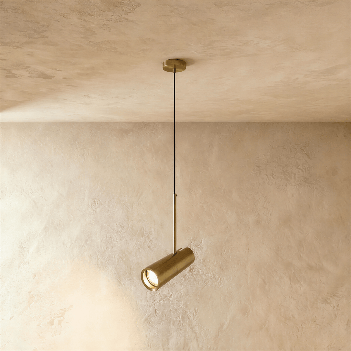 Clérachic single brass-toned cylinder pendant with an angled spot head, hung from a matching brass ceiling plate.