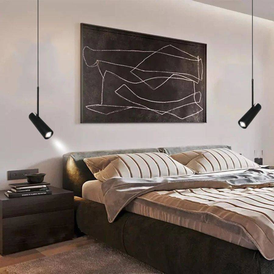 Clérachic two black cylinder pendants framing a bed, each angled spot head casting a small pool of light on the wall.