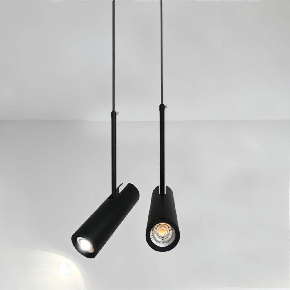 Clérachic close view of two black cylinder pendants on slim rods, one head angled and one straight, glowing warm.
