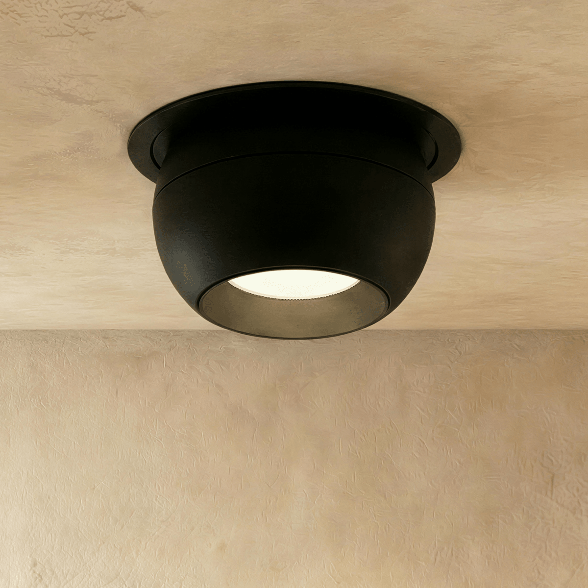 Clérachic black ball-shaped recessed downlight with a round trim and frosted lens, shown flush in a limewashed ceiling.