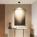 Clérachic black downlight angled to graze a tall framed artwork above a carved console with a bust and sculptural props.